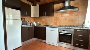 A kitchen with dark cabinets, a white refrigerator, a microwave, a dishwasher, and a stove. - House in a very quiet rural area with easy accessibility. 3.5 km from the beach (Cajiz)