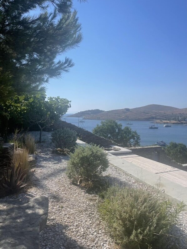 A coastal landscape with a clear sky, rocky terrain, and a view of boats on the water. - Beachfront villa with private pool and sea views (Kea)