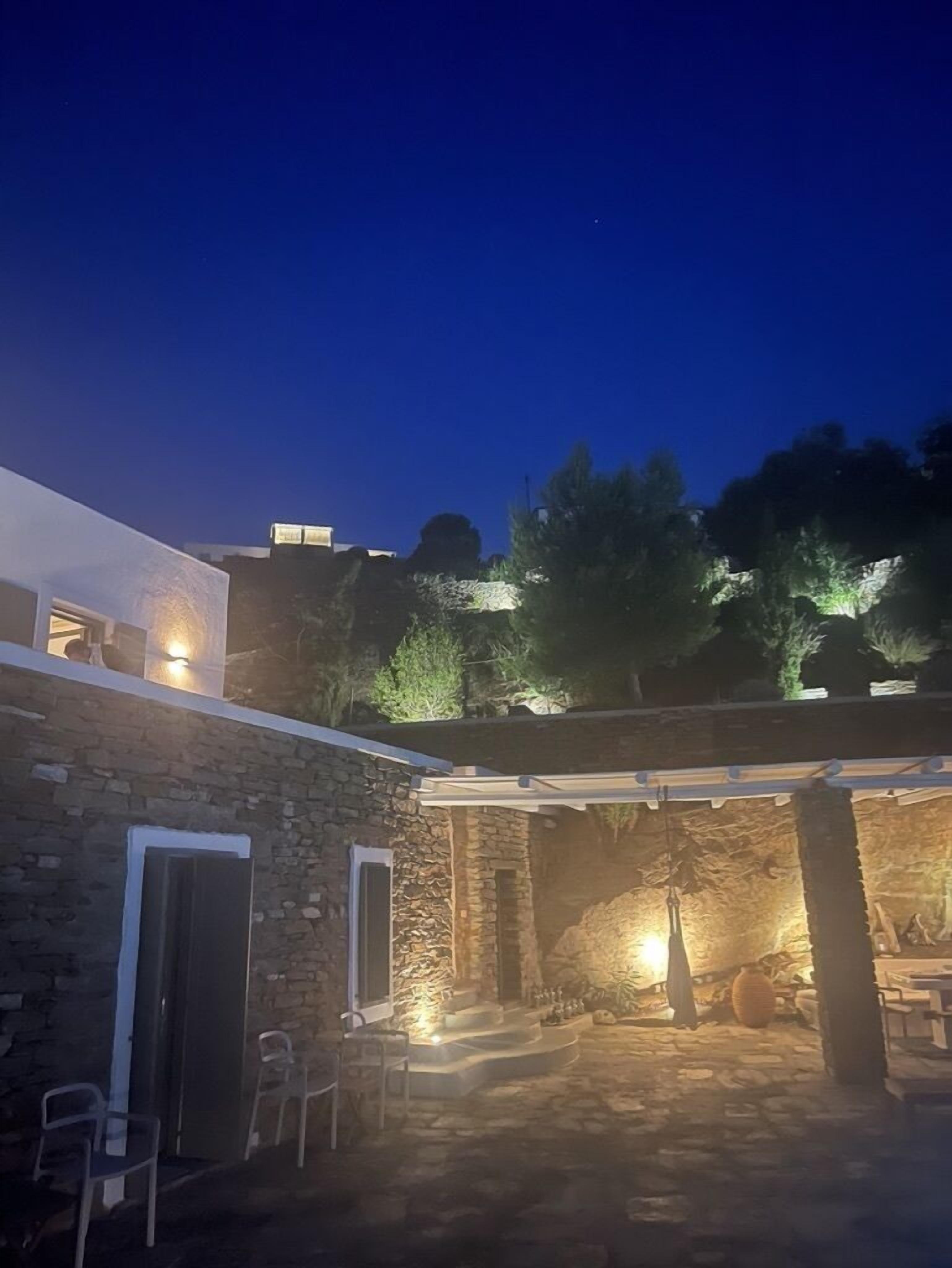 A stone building with a covered patio area, stone walls, and a few chairs.