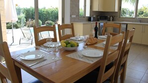 A dining table set for six with plates, cutlery, and a bowl of fruit.