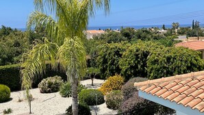 A garden with a palm tree, various shrubs, and a tiled roof.
