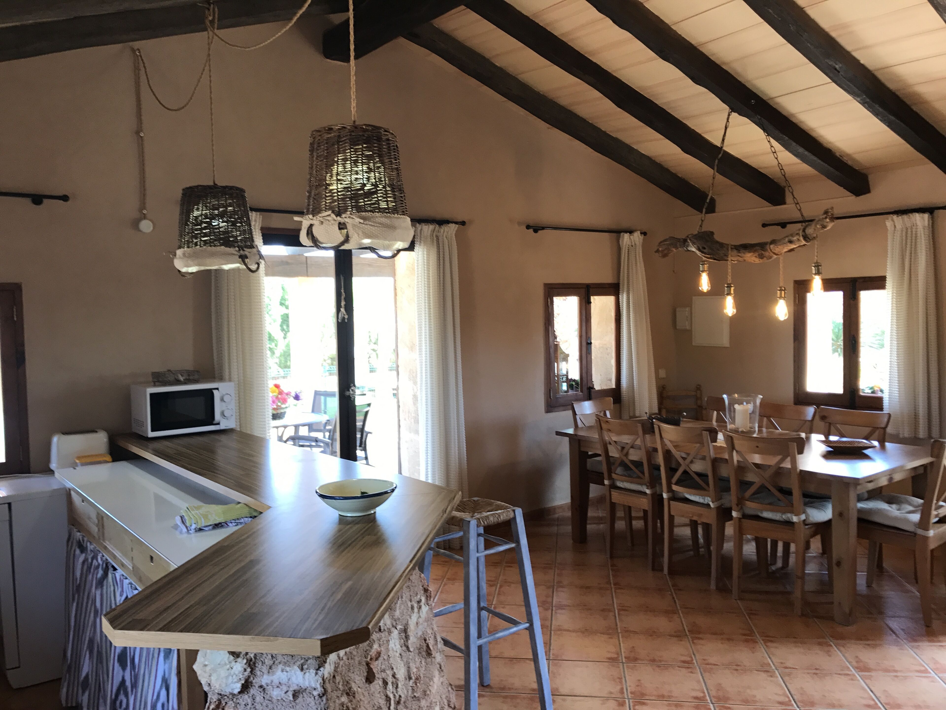 Una cocina con isla de madera, microondas y luces colgantes.