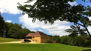 A stone house with a red roof, surrounded by a green lawn and trees. - Renovated Traditional Stone House With Private Salt Water Pool  (Gourdon)