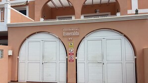 Un edificio residencial con dos puertas blancas grandes, un cartel que indica 'Esmeralda No 9' y un letrero que prohíbe estacionar scooters.
