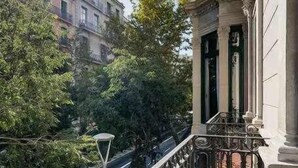 A balcony with ornate black railings, overlooking a street with trees and buildings. - Luxury Apartment on Valencia Street (Barcelona)