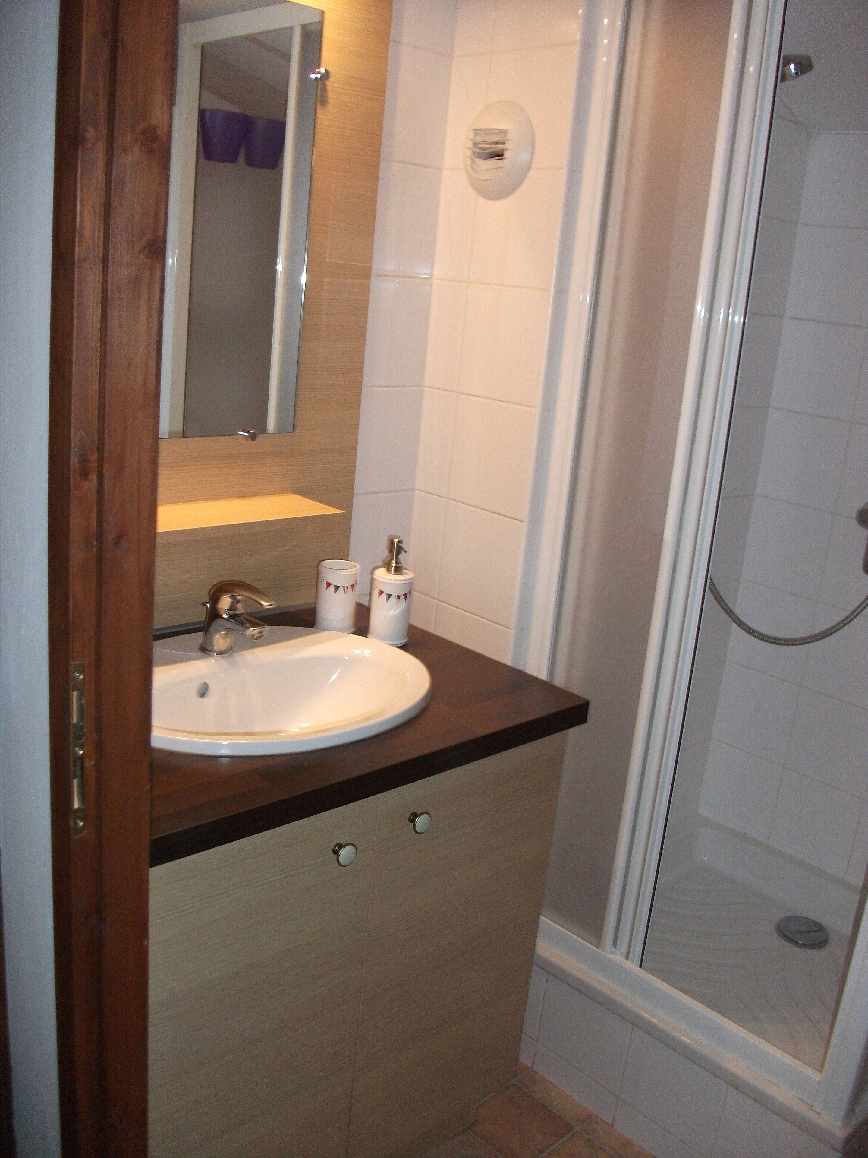 A bathroom with a wooden vanity, a white sink, and a glass shower enclosure.