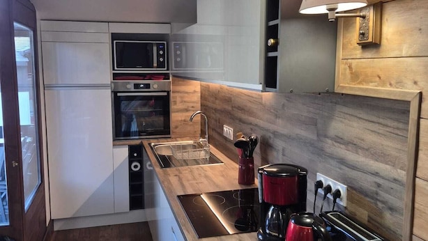 Eine moderne Küche mit eingebauten Geräten, einer Holz Arbeitsplatte und einem Spülbecken.