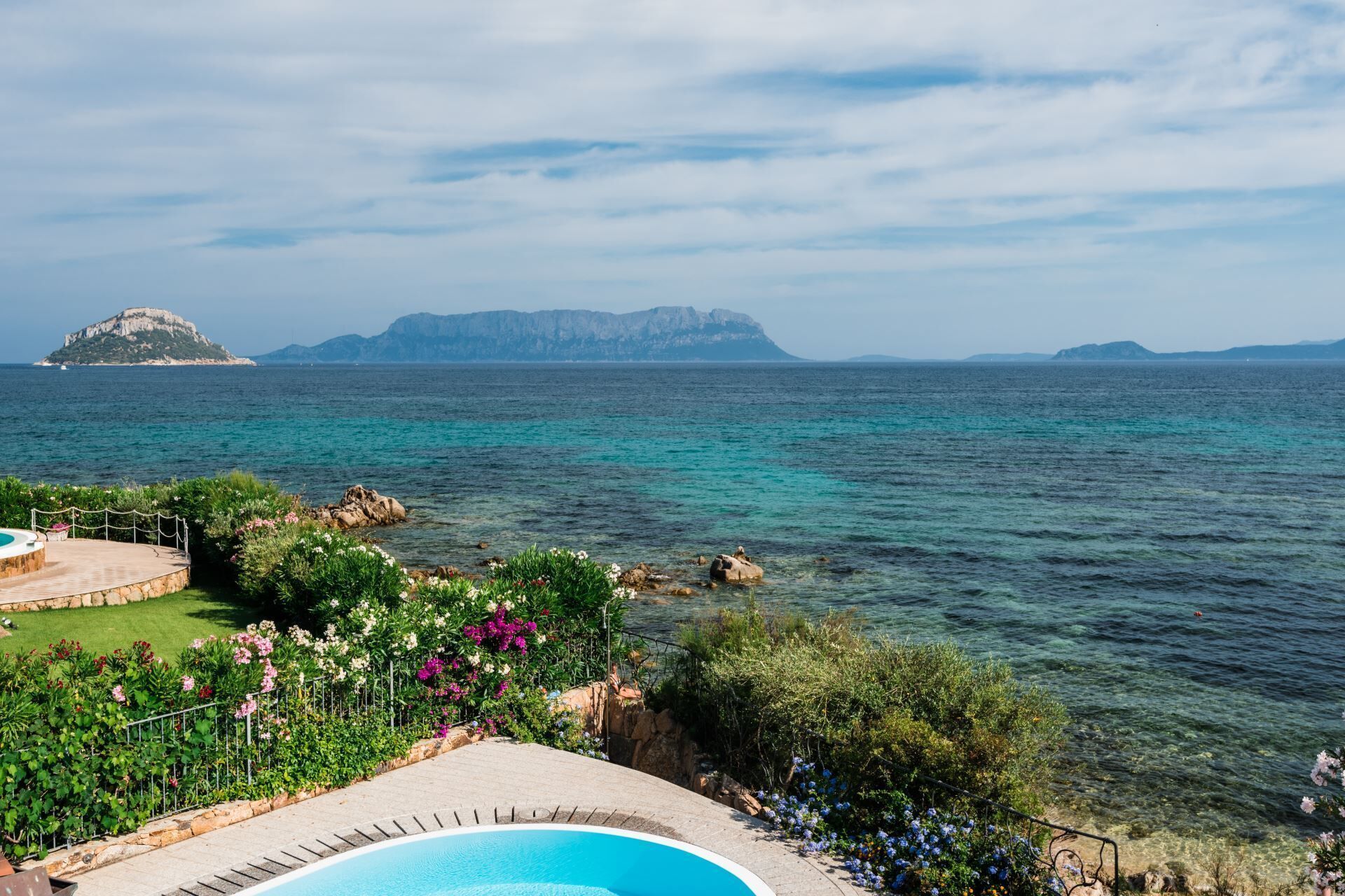 Área da piscina com vista para o mar e ilhas ao longe.
