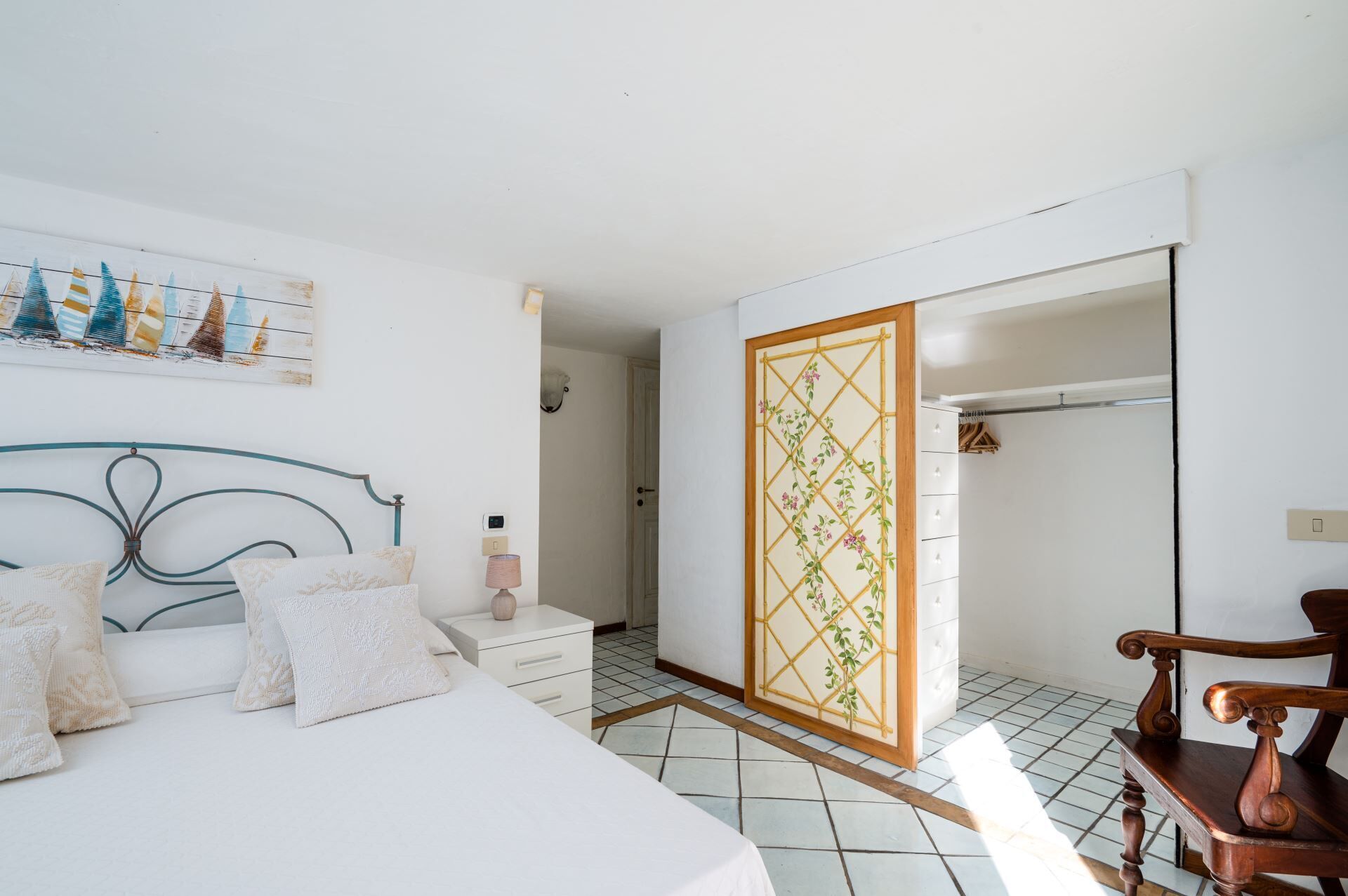 A bedroom with a bed, bedside table, lamp, and a wardrobe.