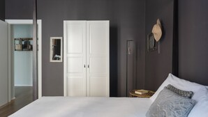 A bedroom with a large bed, a wardrobe, a bedside table, and a wall-mounted lamp. - Happy Travelers Apartment (Como)