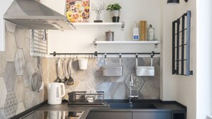 A modern kitchen with a stone backsplash, stainless steel appliances, and a black countertop. - Happy Travelers Apartment (Como)