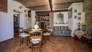 Uma área de refeições com mesa e cadeiras de madeira, um sofá e um espelho decorativo.