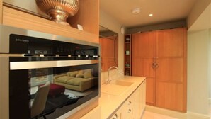 Una cocina moderna con horno empotrado y un amplio ventanal con vistas a una sala de estar.