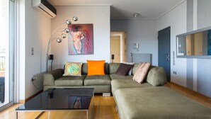 A modern living room with a sectional sofa, a glass coffee table, and a painting on the wall. - Acropolis view Penthouse (Athina)