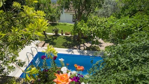 A swimming pool surrounded by lush greenery and flowering plants. - Garden House, Ephesus Holiday Rentals (Selçuk)