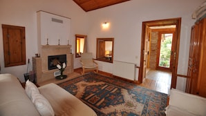 A spacious living room with a fireplace, a large rug, and a wooden ceiling. - Garden House, Ephesus Holiday Rentals (Selçuk)