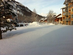 A snow-covered parking area with a building in the background. - Serre Chevalier 1400: Apartment/ flat - La Salle-les-Alpes (La Salle-les-Alpes)