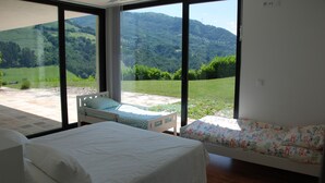 Une chambre avec une grande fenêtre, un lit, une chaise et un canapé.