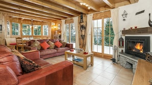 Ein gemütliches Wohnzimmer mit Kamin, Ledersofas und großen Fenstern.