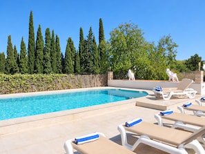 A swimming pool with lounge chairs and a stone wall.