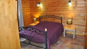 Une chambre dans une cabane en bois, avec un lit, deux lampes de chevet et une porte en bois.