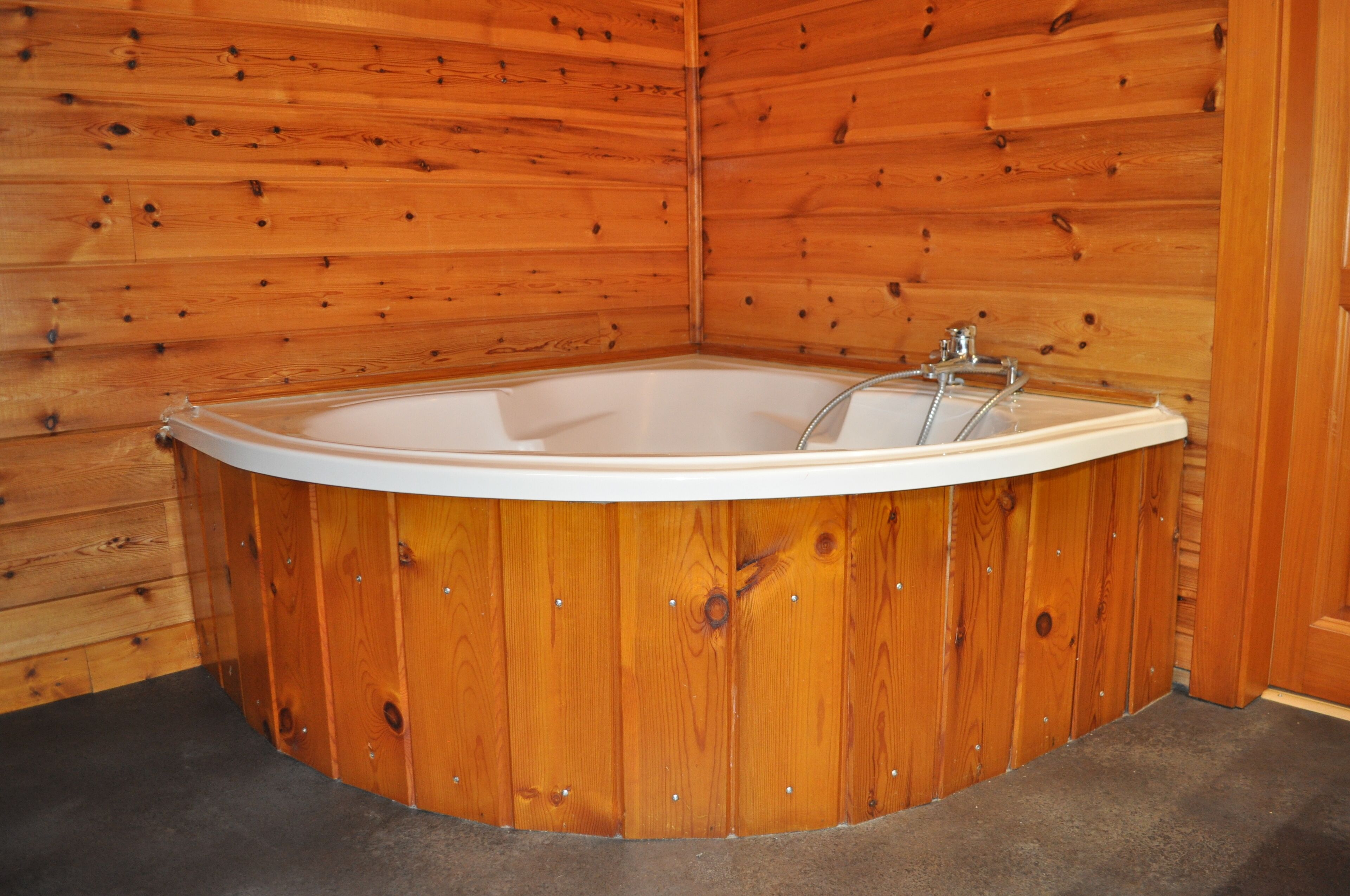 A wooden cabin with a corner bathtub.