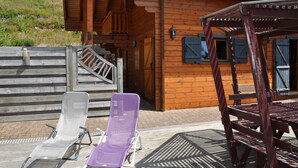 Une cabane en bois avec une véranda, un escalier et deux fauteuils.