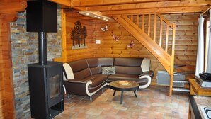 Un salon chaleureux avec une cheminée, un escalier en bois et un canapé.
