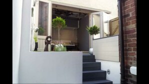 Een modern huis met een overdekte veranda, een trap en buitenplanten.