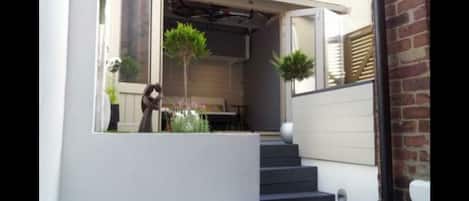 A modern house with a covered porch, a staircase, and outdoor plants.