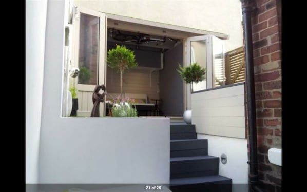 A modern house with a covered porch, a staircase, and outdoor plants.