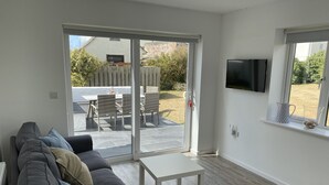 Un salon moderne avec un canapé, une petite table et un téléviseur fixé au mur.