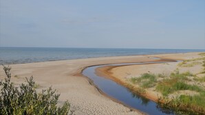 Une plage avec un canal d’eau sinueux et une végétation clairsemée.