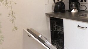 A kitchen with white cabinets, a kettle, a coffee maker, and a dishwasher. - Lovely spacious, luxurious apartment with canal view (Amsterdam)