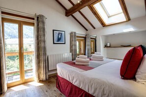 Una habitación de hotel con una cama grande, una ventana con cortinas, un radiador y un tragaluz.