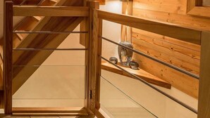 A modern wooden staircase with glass railings and a view of a second-floor area. - Chalet Grand Cru Central 5 Bed with Jacuzzi (Chamonix-Mont-Blanc)