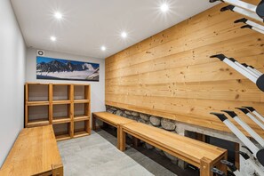 A ski lodge interior with wooden benches, a stone wall, and ski equipment.