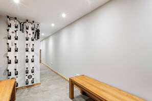 A hallway with a white wall, a wooden bench, and a white curtain with black patterns. - Chalet Grand Cru Central 5 Bed with Jacuzzi (Chamonix-Mont-Blanc)