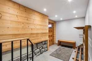 Un intérieur en bois avec une cheminée en pierre, un banc et une étagère en bois.