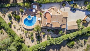 Vue aérienne d’une propriété résidentielle dotée d’une piscine, d’un patio couvert et d’un jardin aménagé.