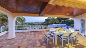 Une terrasse dotée d’un sol à motifs, une table dressée pour le repas et une vue sur la mer.