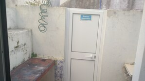 Un espacio reducido y cerrado con un banco, una puerta que indica 'acceso reservado' y un cilindro de gas rojo.