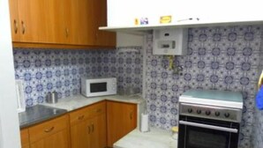 Una cocina compacta con armarios de madera, un microondas y una estufa.