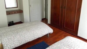 Una habitación con dos camas, un armario de madera, una puerta y un espejo.