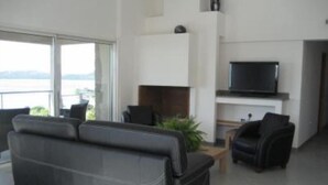 Una sala de estar moderna con un sofá de cuero negro, un televisor y una planta.