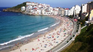 A coastal cityscape with a wide beach, buildings along the shore, and a clear view of the sea.