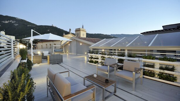 Une terrasse sur le toit avec des sièges extérieurs, une serre et une vue sur le paysage environnant.