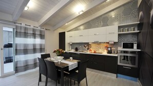 Une cuisine moderne avec des meubles de rangement de couleur sombre, un coin repas avec une table et des chaises, et un four à micro-ondes.