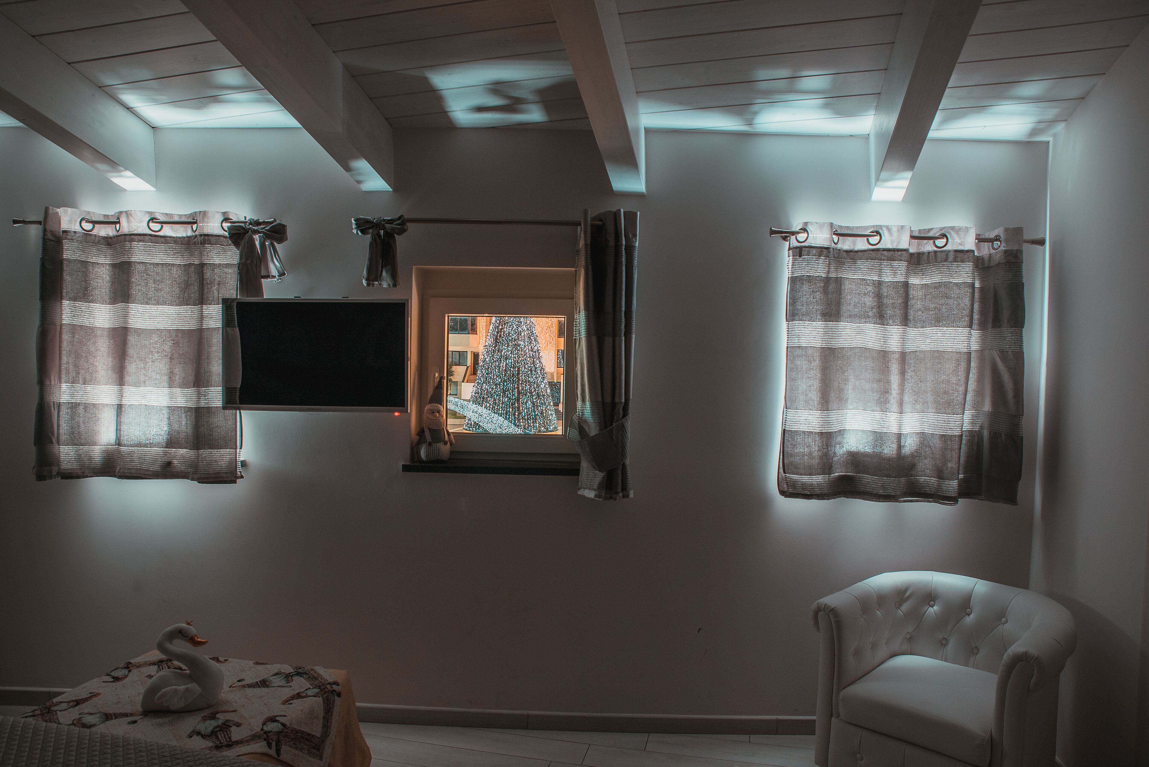 Ein Zimmer mit Fernseher an der Wand, einer Schwaneinrichtung und einem Sessel.