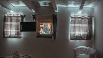 Ein Zimmer mit Fernseher an der Wand, einer Schwaneinrichtung und einem Sessel.